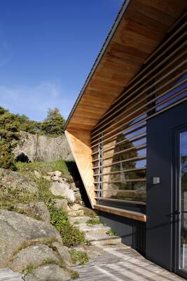 Modern contrasting facade with wooden louvers on a rocky site