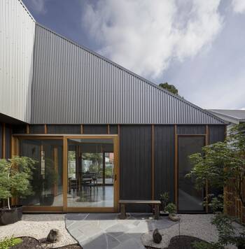 Modern facade with contrasting metal and wood: corrugated roofing and dark timber panels