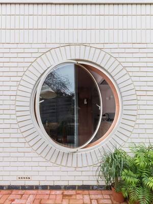 Minimalist white facade with a circular portal window