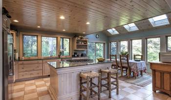 Spacious kitchen-dining area with wooden ceiling and panoramic windows in a country house