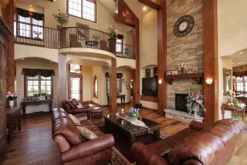 Luxurious double-height interior with rustic elements and a monumental stone fireplace