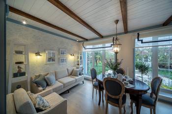 Provencal coziness with a modern accent: interior of a bright living-dining room with wooden beams