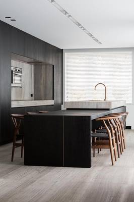 Minimalist kitchen with contrasting textures: dark wood and copper accents